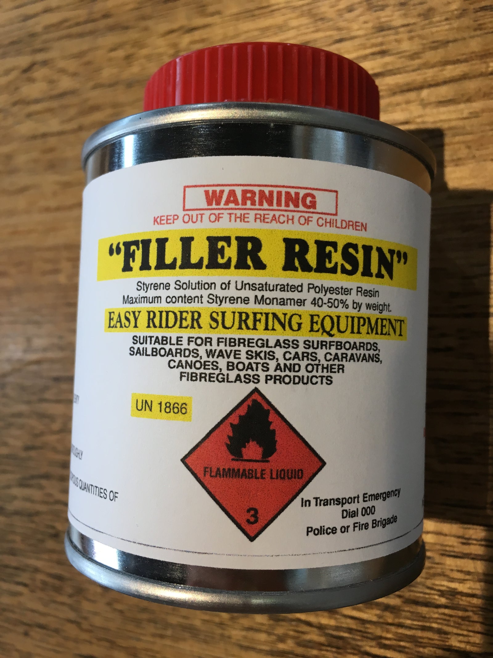 A tin of CV Filler Poly Resin with a label indicating it is a 40% resin easy rider surfboard fin, suitable for fiberglass surfboards, with a flammable liquid warning.
